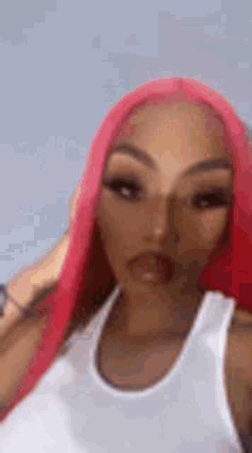 a woman with red hair is wearing a white tank top and taking a selfie .