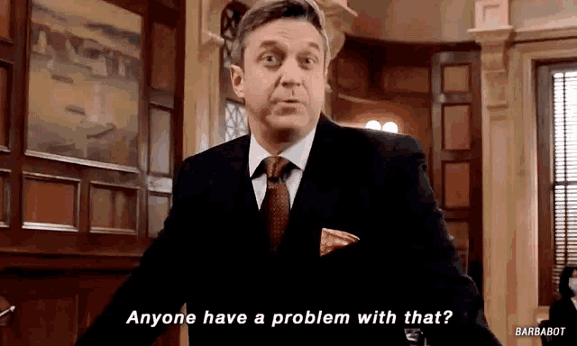 a man in a suit and tie is asking if anyone has a problem with that