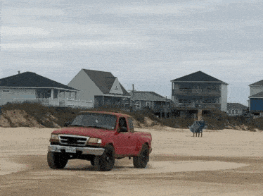a red pickup truck with a license plate that says twp-744 is driving on a sandy beach