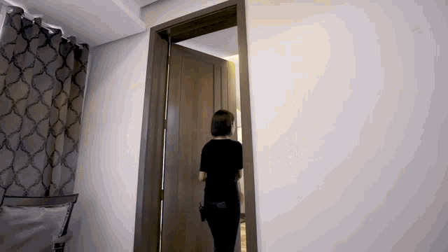 a woman in a black shirt is walking through a door