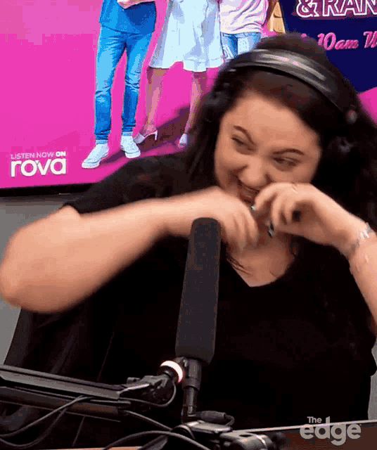 a woman wearing headphones is laughing in front of a sign that says " listen now on rova "
