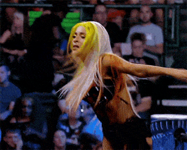 a woman with yellow hair is dancing in front of a crowd of people