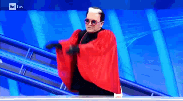 a man in a red cape and sunglasses is dancing on a rai hd screen