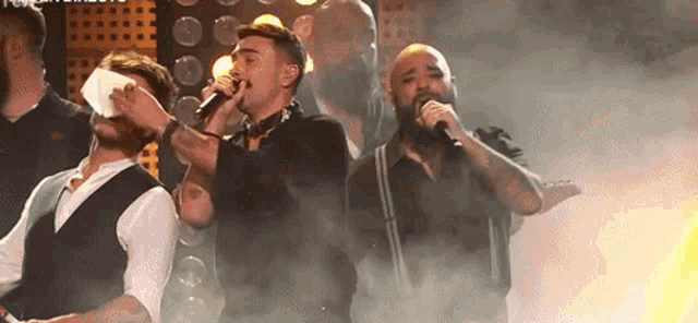 a group of men singing into microphones on stage
