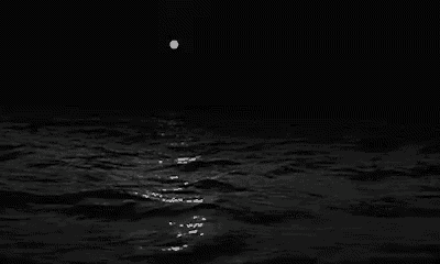 a black and white photo of a full moon over a body of water