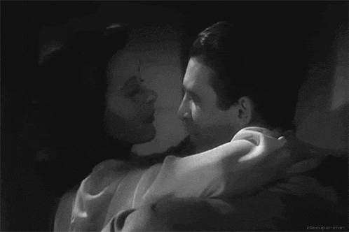 a black and white photo of a man and woman kissing .