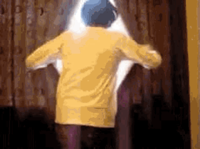 a person wearing a yellow jacket and a blue hat is standing in front of a door .