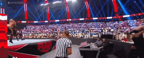 a referee is standing in the middle of a wrestling ring during a match .
