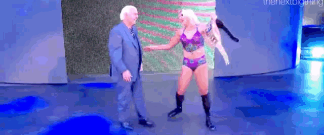 a man in a suit is standing next to a woman in a purple bikini .
