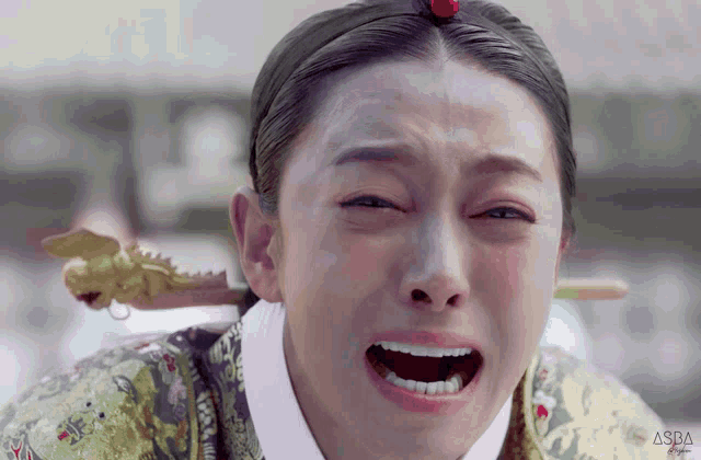a woman with a dragon on her head is crying with aspa written on the bottom right