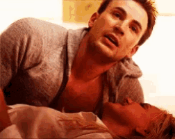 a man and a woman are laying on a bed and the man is looking at the woman 's chest .