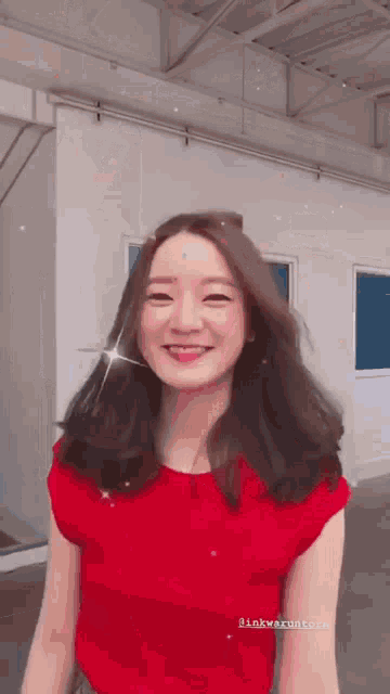 a woman wearing a red shirt is smiling for the camera