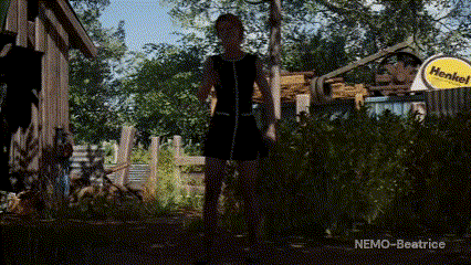 a woman in a black dress is standing on a chain in a backyard .