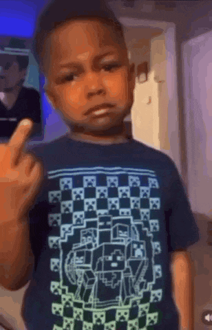 a young boy is giving the middle finger while wearing a minecraft t-shirt .