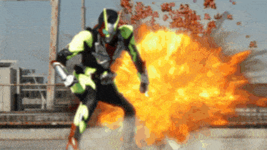 a man in a green and black superhero costume stands in front of a large explosion