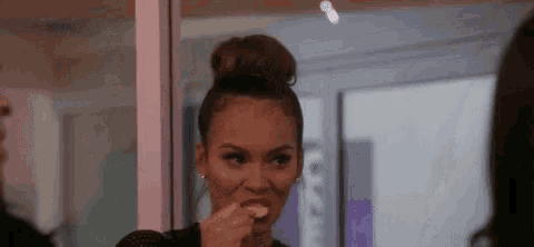 a woman with her hair in a bun is eating a piece of food .