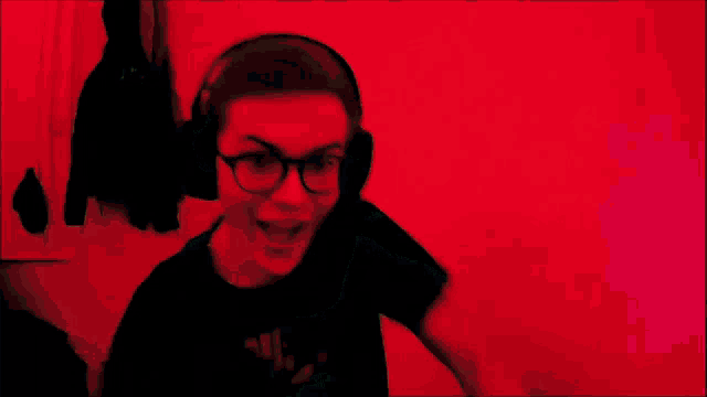 a woman wearing headphones and glasses is making a funny face in front of a red background