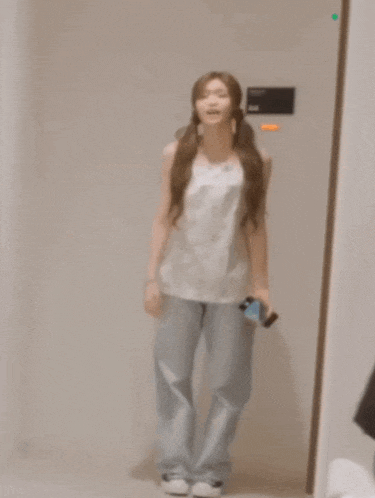 a woman standing in front of a mirror holding a cellphone
