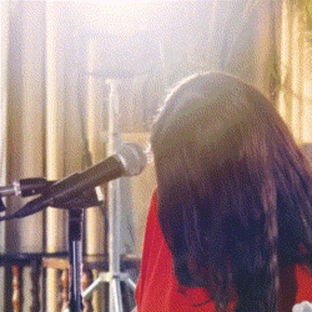 a woman singing into a microphone in front of a curtain