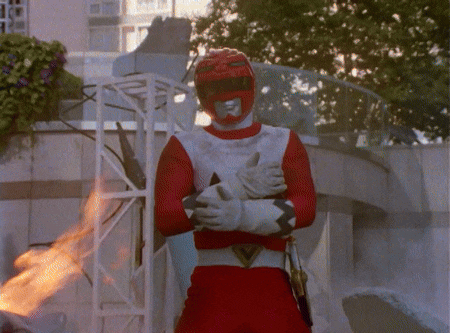 a red power ranger giving a thumbs up in front of a building