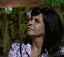 a close up of a woman 's face with a blurred background of trees .