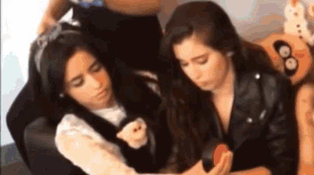 two girls are sitting on a couch and one is holding a stuffed animal