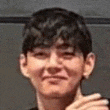 a close up of a young man making a funny face while holding his hand to his chin .