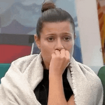 a woman wrapped in a towel is covering her mouth with her hand .