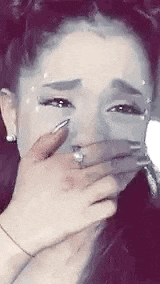 a woman is crying while covering her face with her hand .