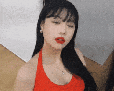 a woman wearing a red tank top and red lipstick looks at the camera