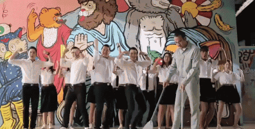 a group of people are dancing in front of a wall with a drawing of a bear on it