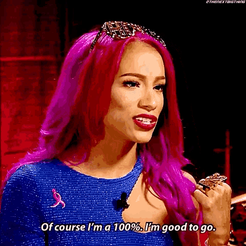 a woman with pink hair is wearing a blue dress and a ring and says of course i 'm a 100 %