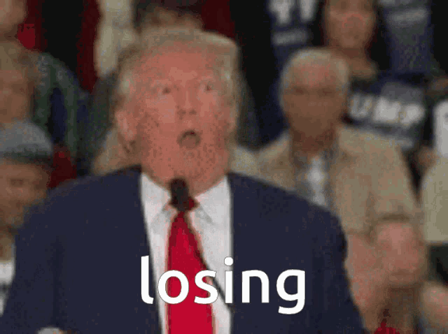 a man in a suit and tie is speaking into a microphone and the word losing is visible behind him