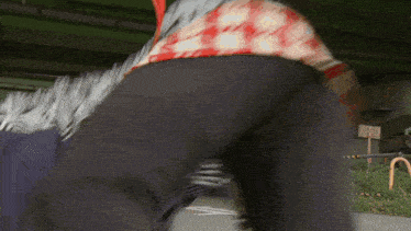 a person wearing black pants and a red and white shirt is standing on a street