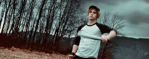 a young man is holding a baseball bat in a field in front of trees .