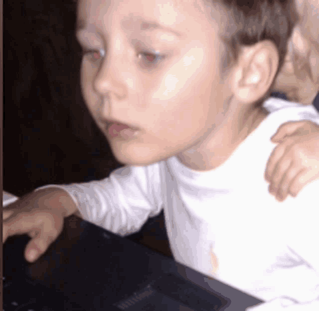 a little boy with red eyes is using a laptop computer