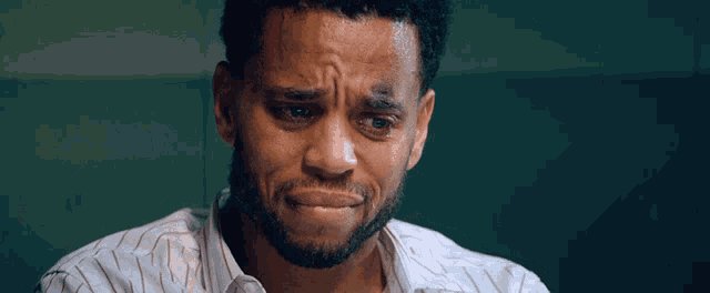 a man with a beard and a white shirt looks sad