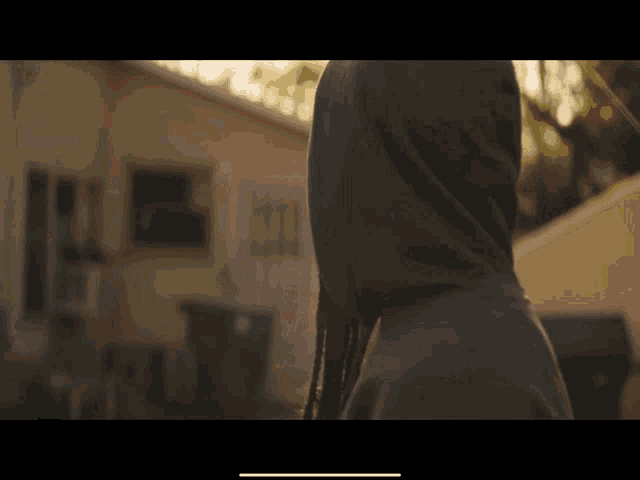 a person wearing a hooded jacket is standing in front of a house