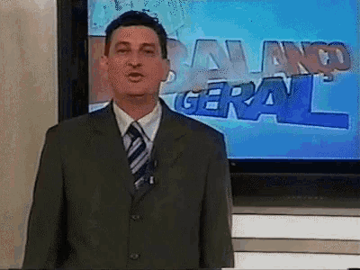 a man in a suit and tie is standing in front of a tv screen that says balanco geral