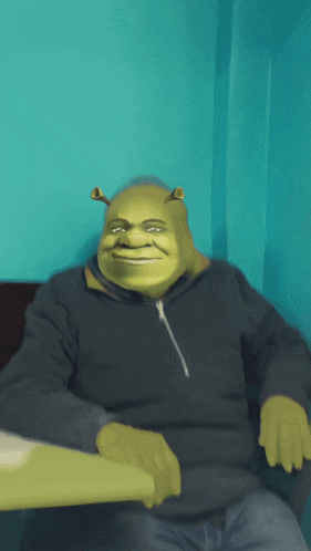 shrek is sitting at a table wearing a black jacket