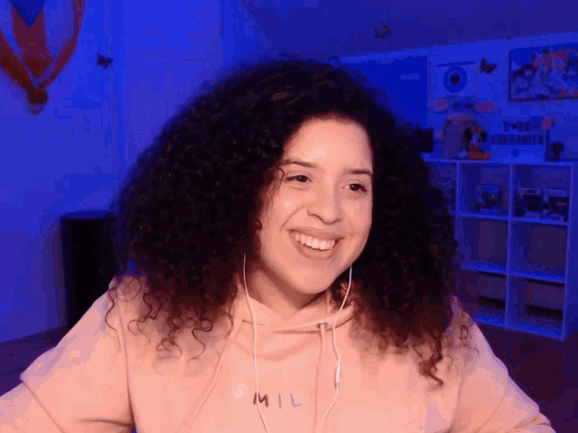 a woman with curly hair wearing a pink hoodie that says smil