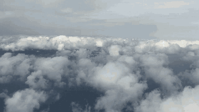 an aerial view of a cloudy sky with a mountain in the distance