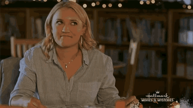 a woman is sitting at a table with a sign that says hallmark movies and mysteries