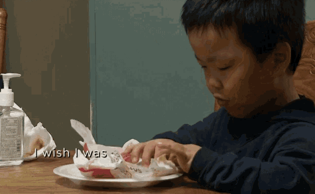 a young boy sitting at a table with a plate of food and the words " i wish i was "
