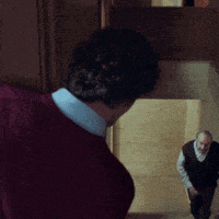 a man in a red sweater is standing in front of another man in a vest