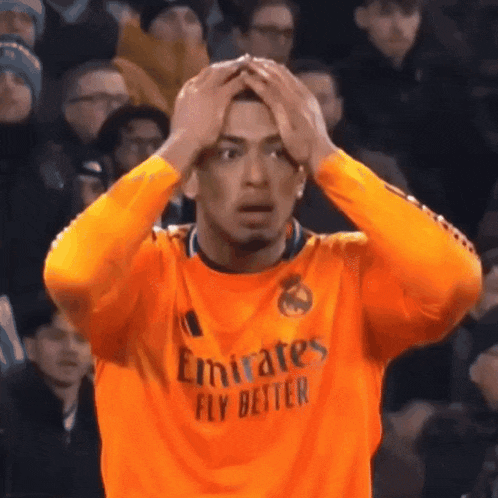 a man wearing an orange emirates fly better jersey