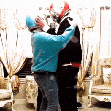 a man in a blue sweater is hugging another man in a black jacket
