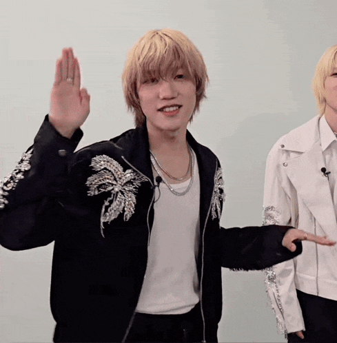 a man wearing a black jacket with sequins on the sleeves is giving a high five