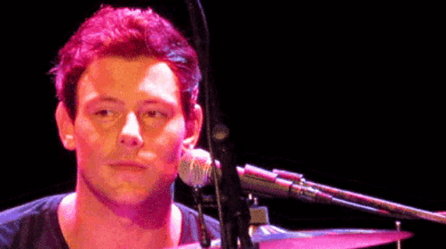 a man is playing drums and singing into a microphone on a stage .