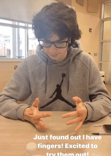 a boy wearing a grey jordan sweatshirt sitting at a table